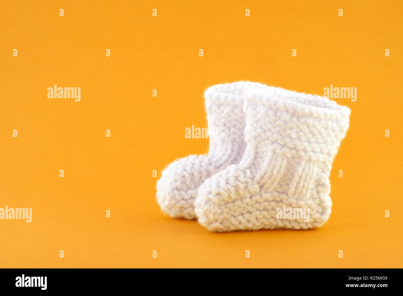 Par de calcetines bebé pequeño sobre fondo naranja Foto de stock