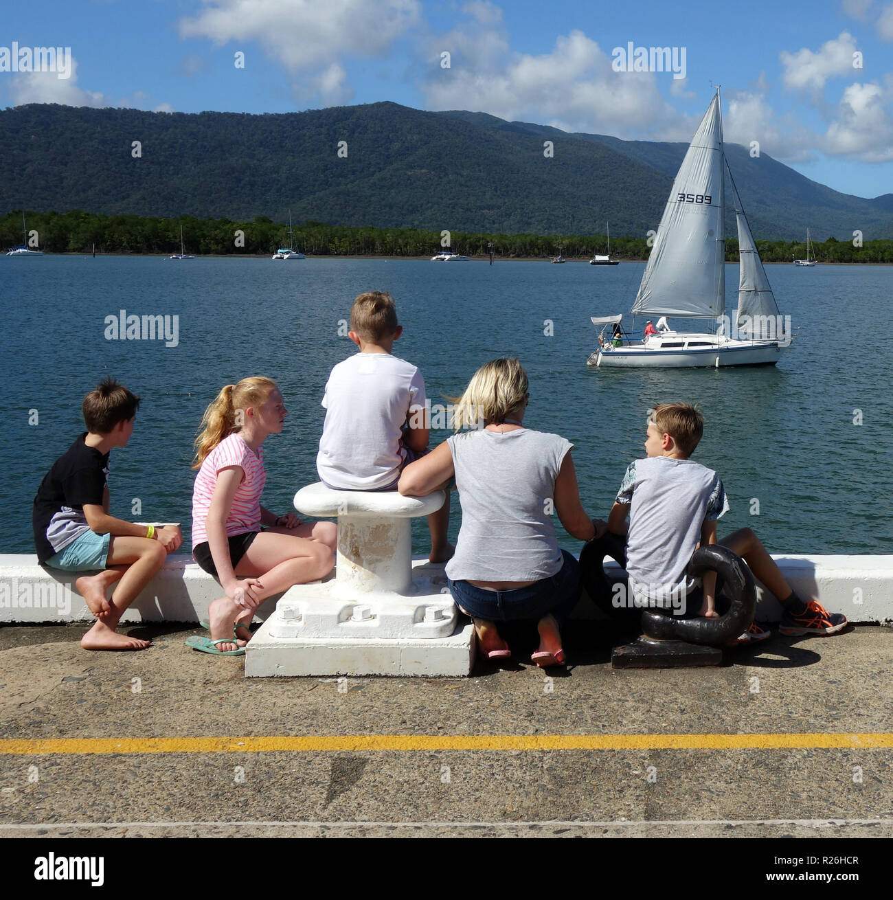 Familia viendo pasar velero en Trinity Inlet, Cairns, Queensland, Australia. No, señor o PR Foto de stock