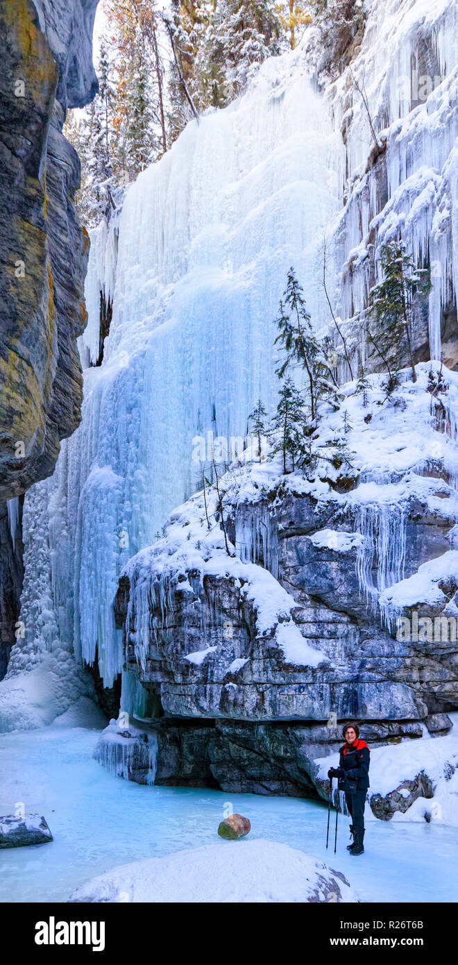 Mujer 42,749.08949 en una profunda nevadas invernales Frozen River Canyon (cañón del río Maligne) mirando las paredes de hielo congelado caídas de hielo Foto de stock