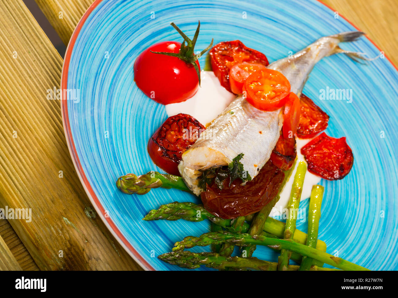 Plato de pescado - bacaladilla horneado con tomates secados al sol,  espárragos y cremosa salsa de ajo Fotografía de stock - Alamy