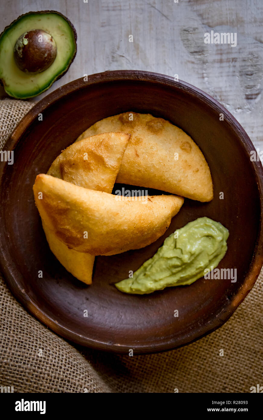 La comida colombiana venezolana. Typicals venezolano empanadas de maíz con carne en recipiente de barro con salsa de aguacate. Foto de stock