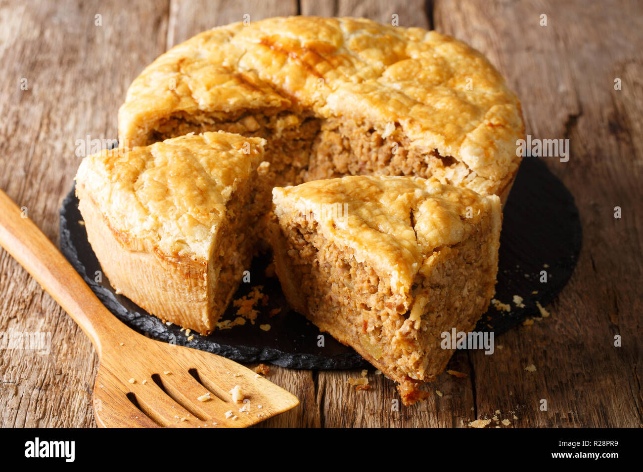 Tourtiere receta tradicional de Francés canadiense empanada rellena con carne de cerdo, puré de patata y especias de cerca en la tabla horizontal. Foto de stock