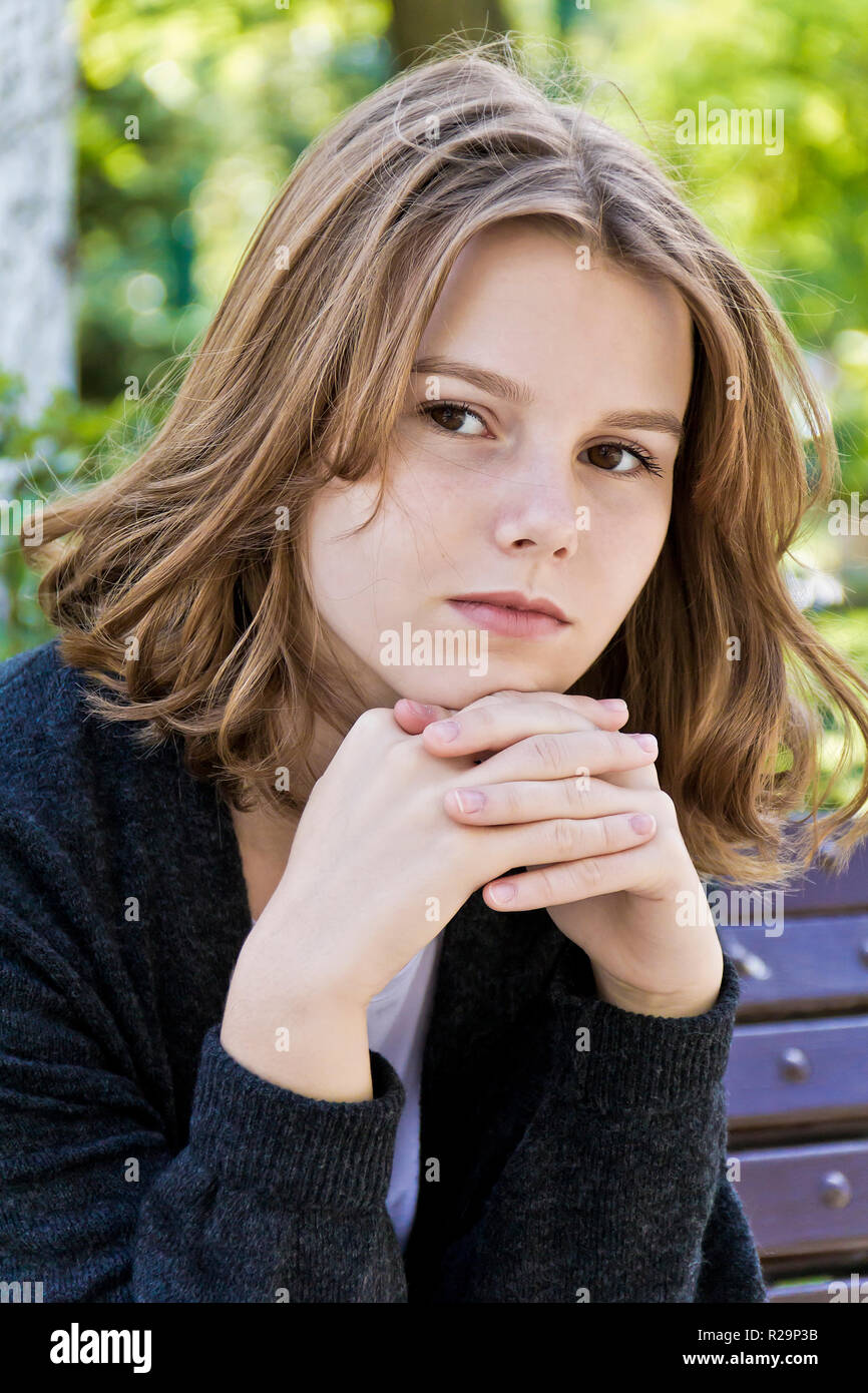 Pensando chica con 14 años están sentados en el banquillo Fotografía de  stock - Alamy