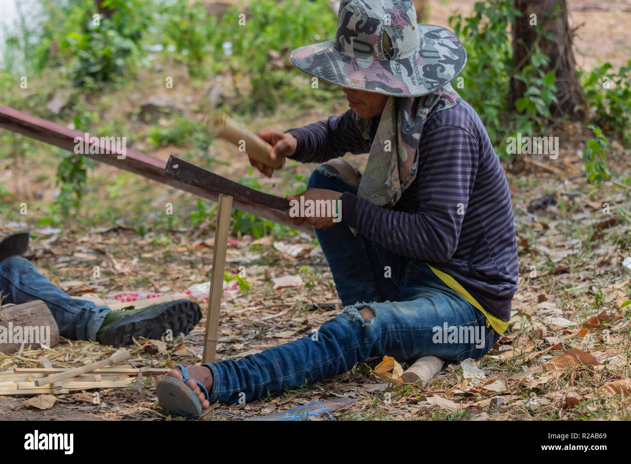 Don Det, Laos - Abril 24, 2018: Local hombre haciendo trabajos manuales con bambú cerca del río Mekong Foto de stock