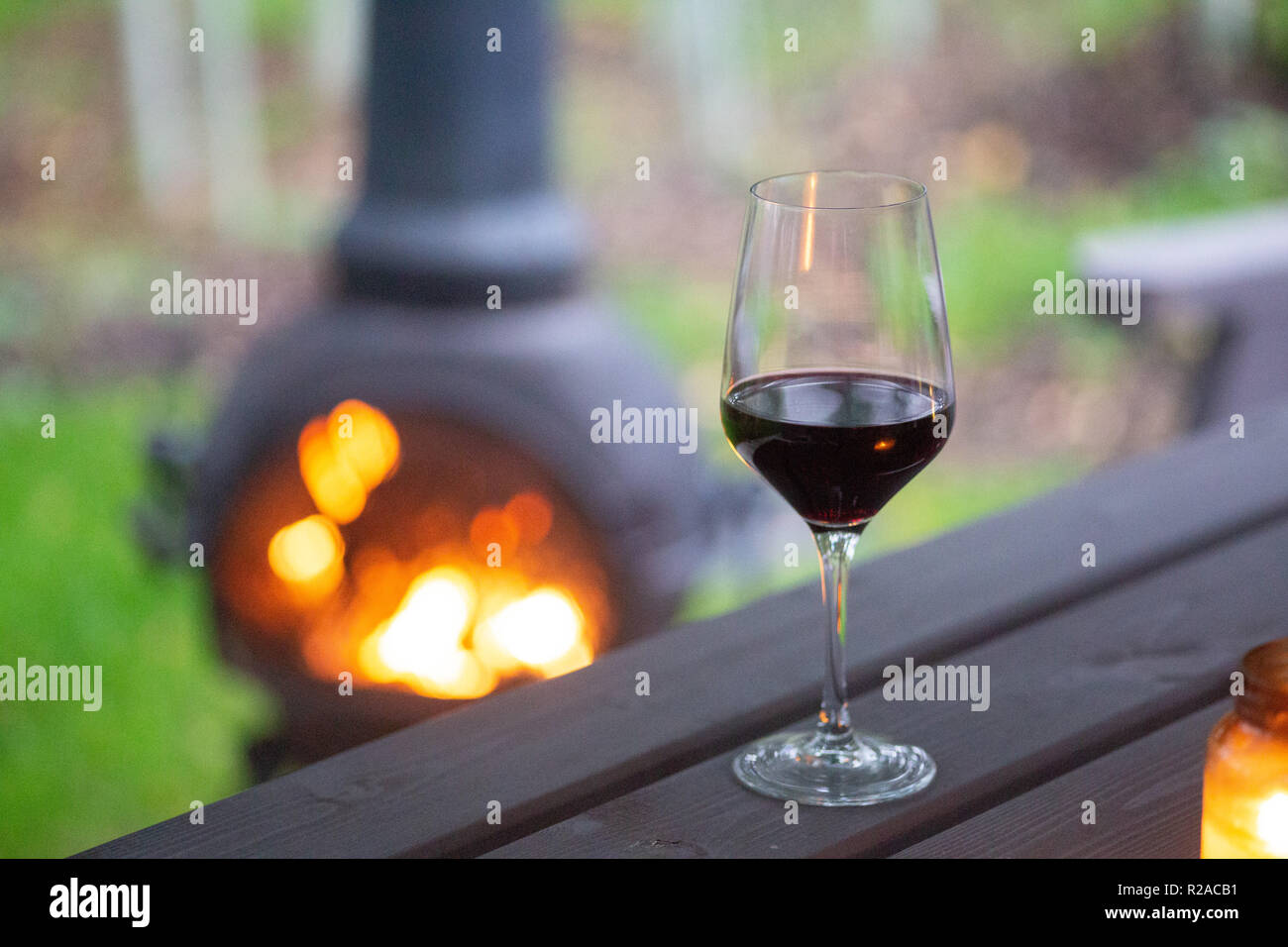 Copa de vino tinto junto a una cálida y acogedora chimenea Foto de stock