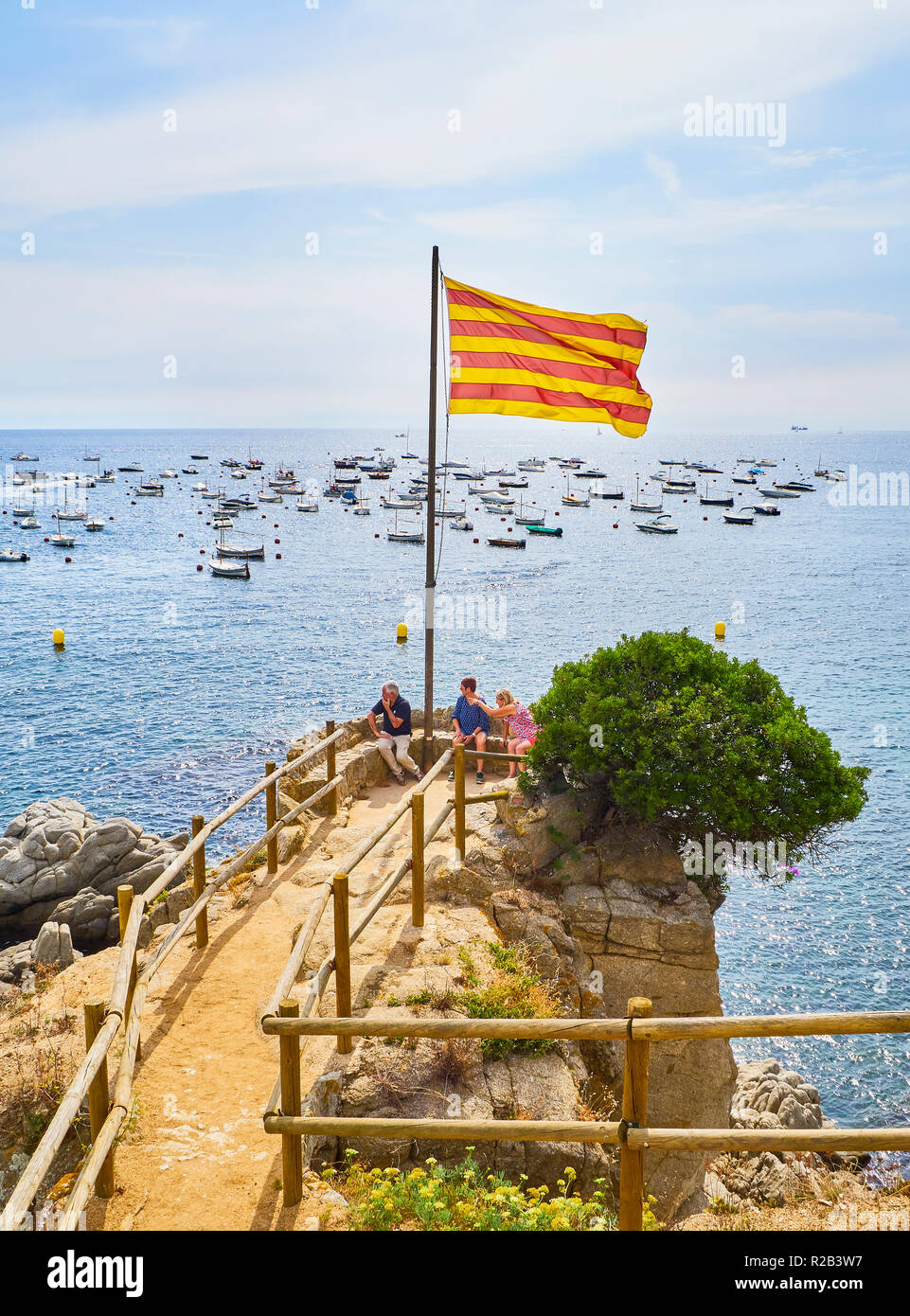 Los turistas que visitan Punta dels Burricaires viewpoint bajo la bandera oficial de Cataluña, Calella de Palafrugell, Girona, Costa Brava, Cataluña, España Foto de stock
