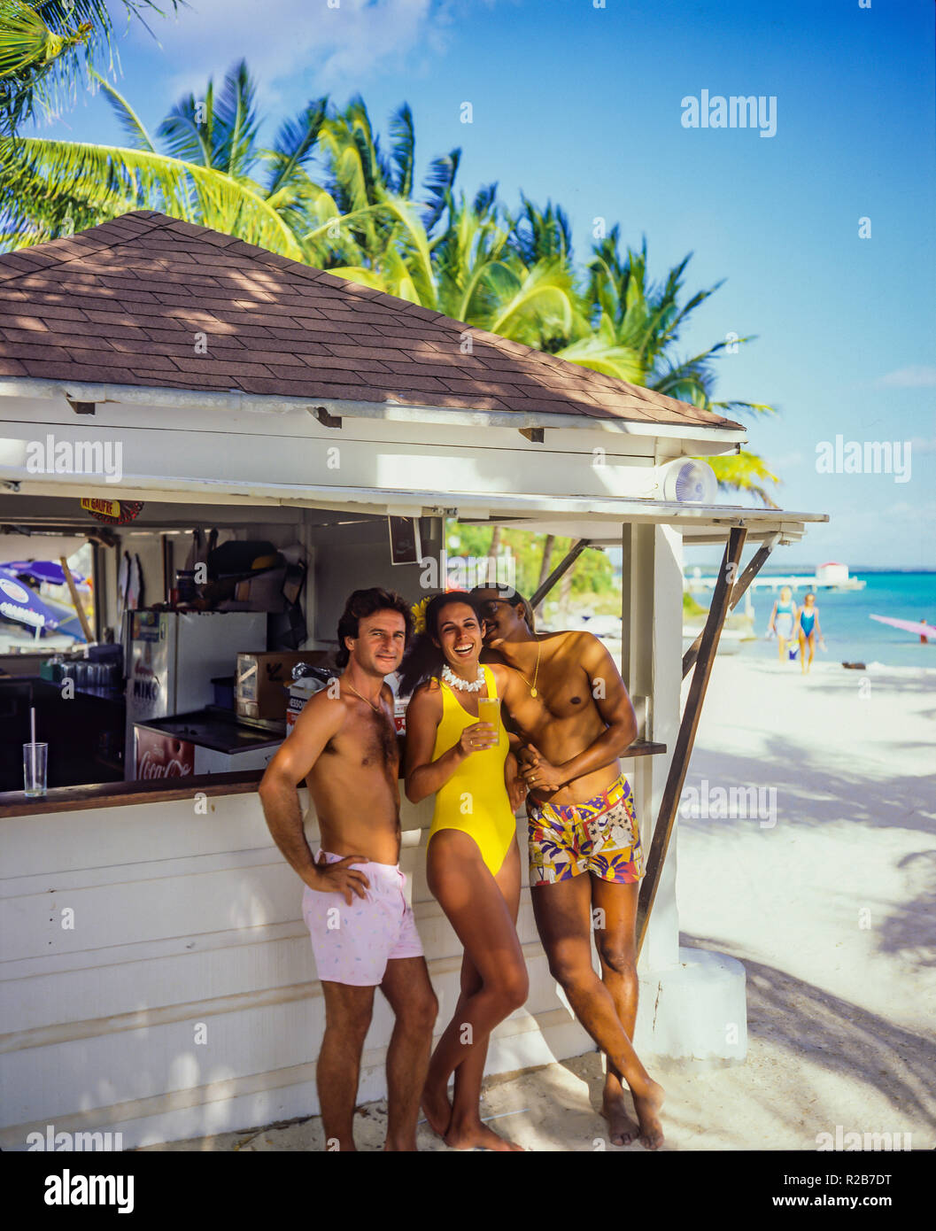 Mujer joven y 2 jóvenes divirtiéndose en el bar de la playa, playa tropical, Saint-François, Guadalupe, Antillas Francesas, Foto de stock