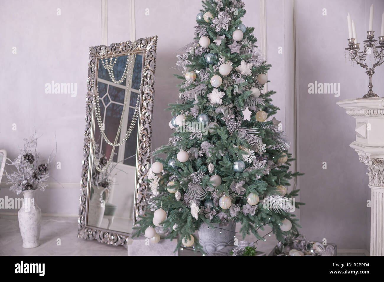 Decorado en blanco y plata grande árbol de navidad con regalos en un  interior de lujo. Año Nuevo en casa.La Navidad interior con espejo grande y  la decoración de navidad, ornamentos. vacaciones
