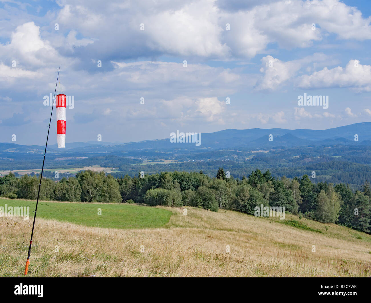 Rojo y Blanco cono de viento en un paisaje de colinas con bosques Foto de stock