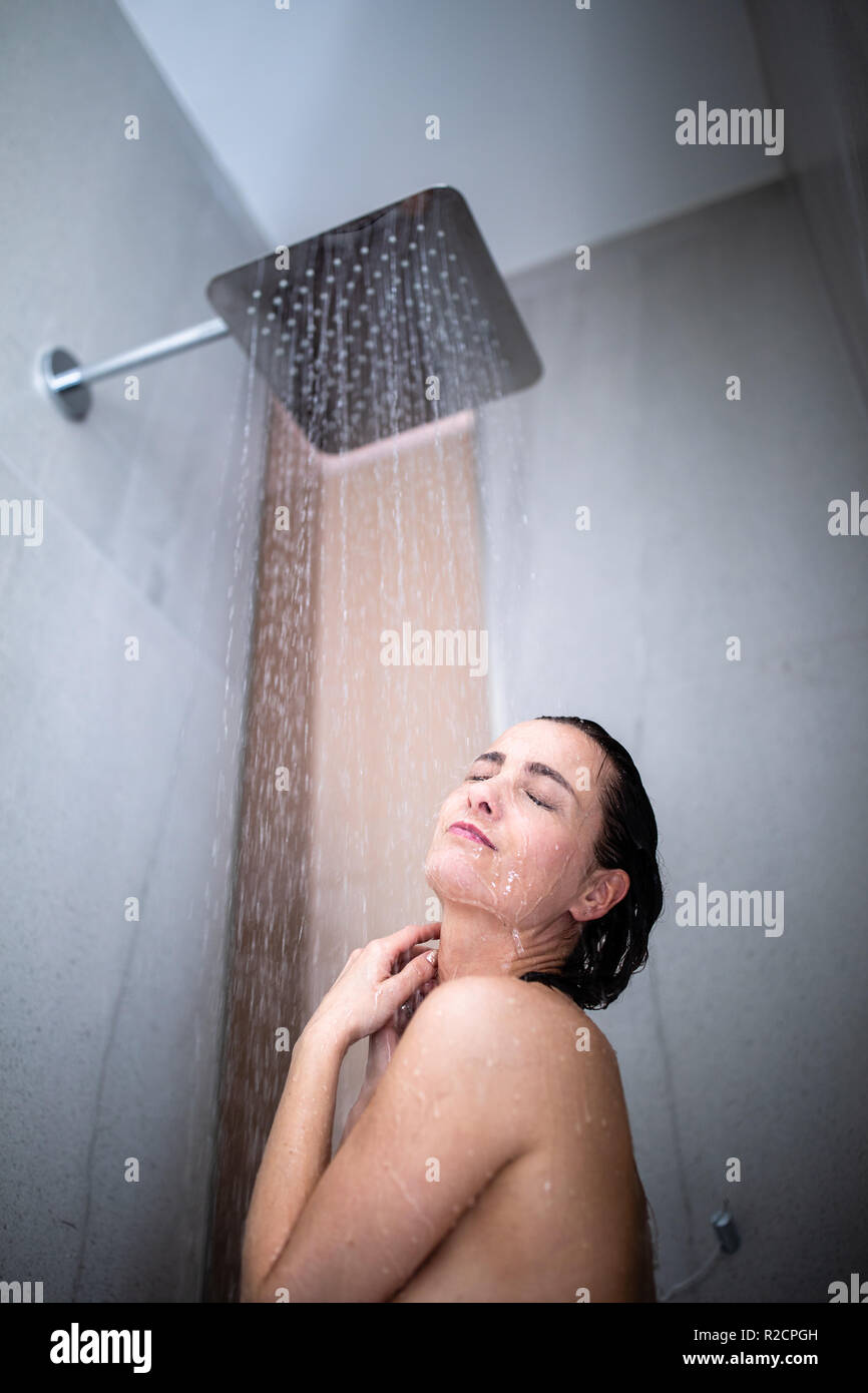 Mujer tomando una larga ducha caliente lavar su cabello con un moderno  cuarto de baño de diseño Fotografía de stock - Alamy