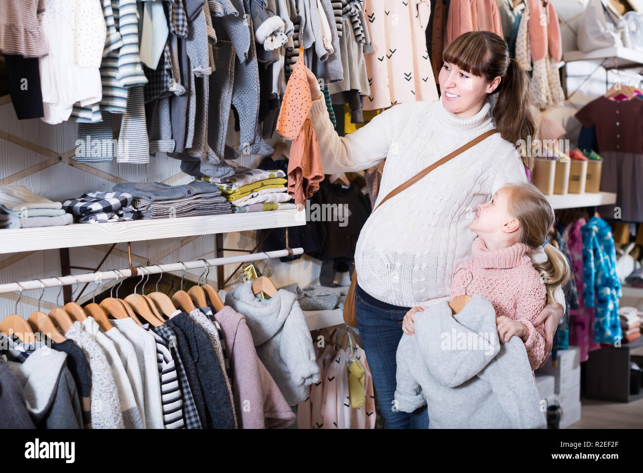 Madre embarazada y niña elegir ropa para bebé en almacén de paños para  niños Fotografía de stock - Alamy