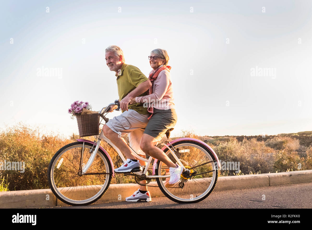 Dos altos hombre y mujer juntos en una vieja bicicleta la actividad al aire libre. La felicidad y la libertad del concepto de trabajo. Los rayos de sol y sonrisas. Foto de stock