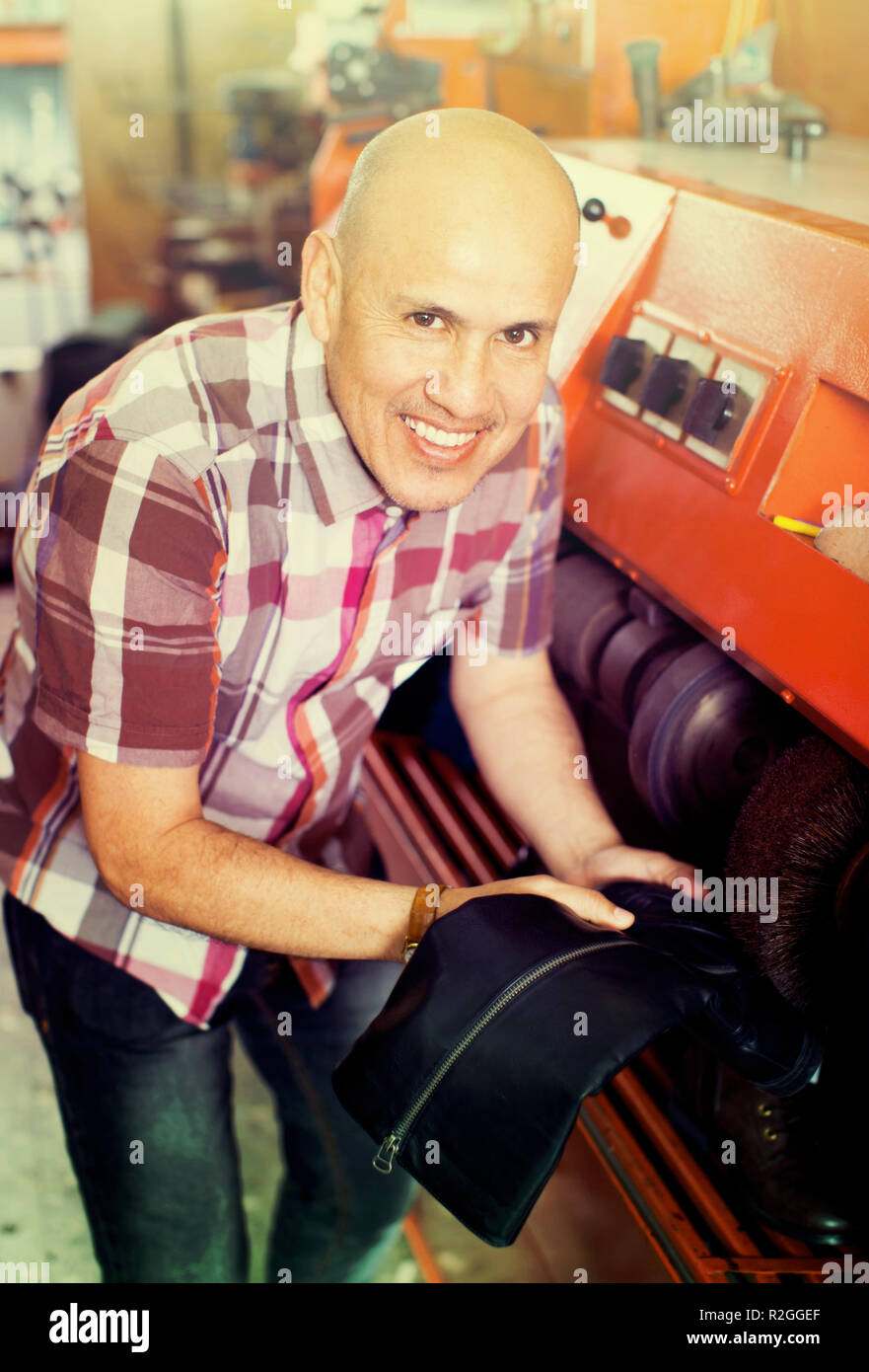 Profesional artesano eficiente calzado pulido en la máquina en el atelier de zapata Foto de stock