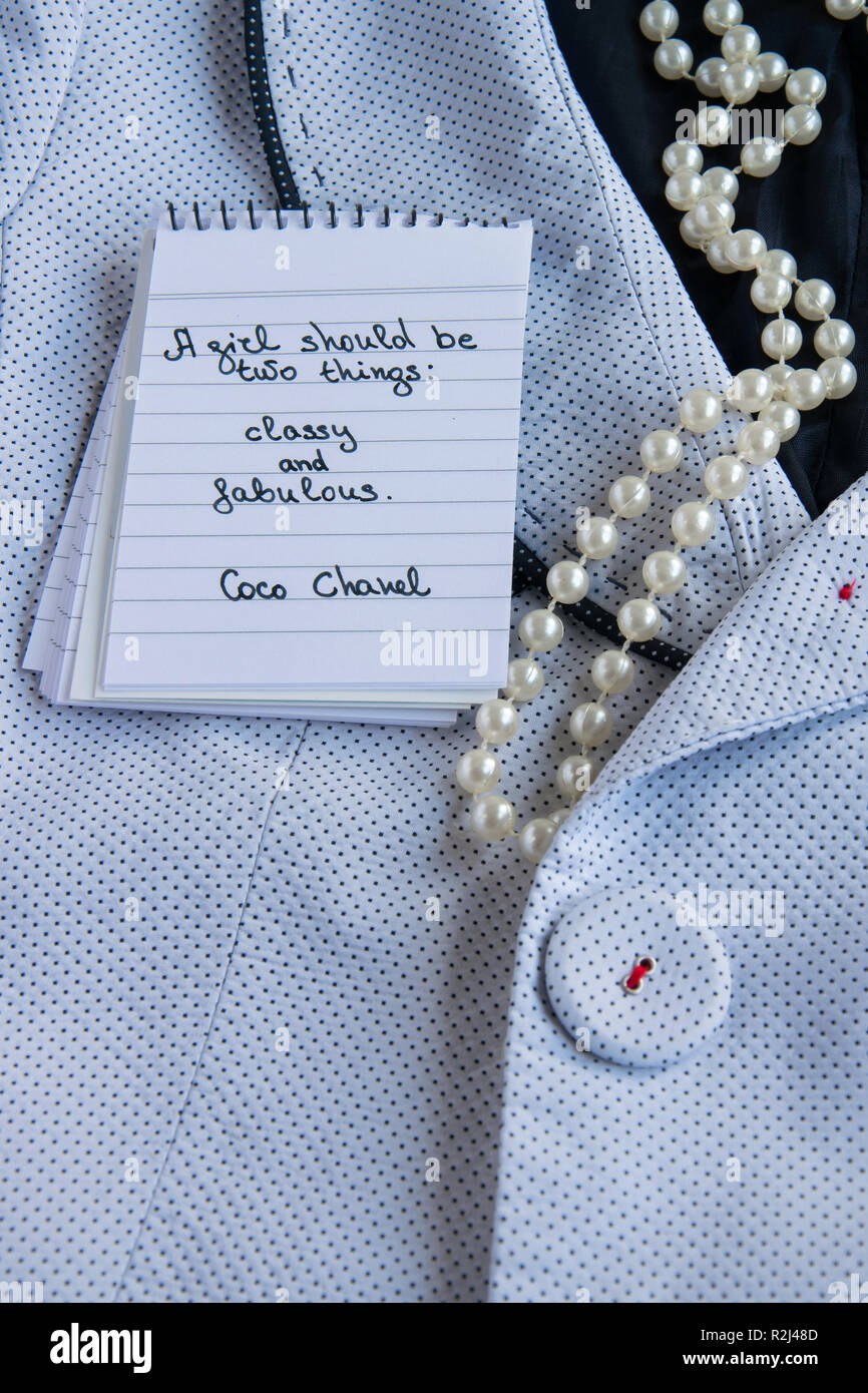 Coco Chanel cita escrita en un bloque nota, Pearl accesorios y un elegante  chaqueta ,inspiración frase "Una niña debe ser dos cosas: elegante y  fabulou Fotografía de stock - Alamy