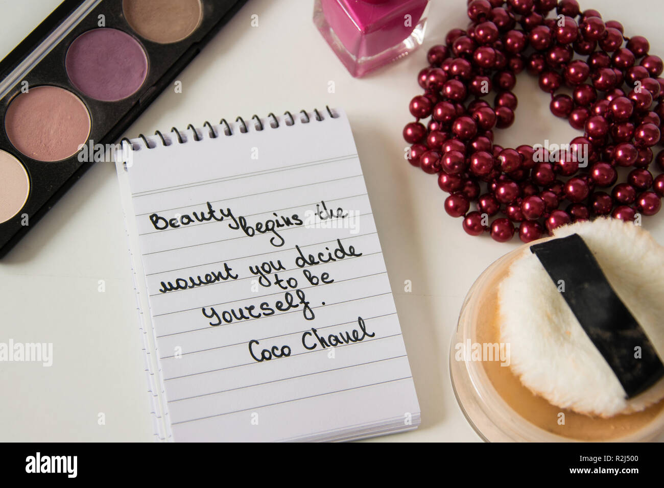 Coco Chanel cita escrita en un bloque nota, Pearl accesorios y maquillaje  sobre fondo blanco, inspiración frase 'Belleza comienza en el momento en  que usted decida Fotografía de stock - Alamy