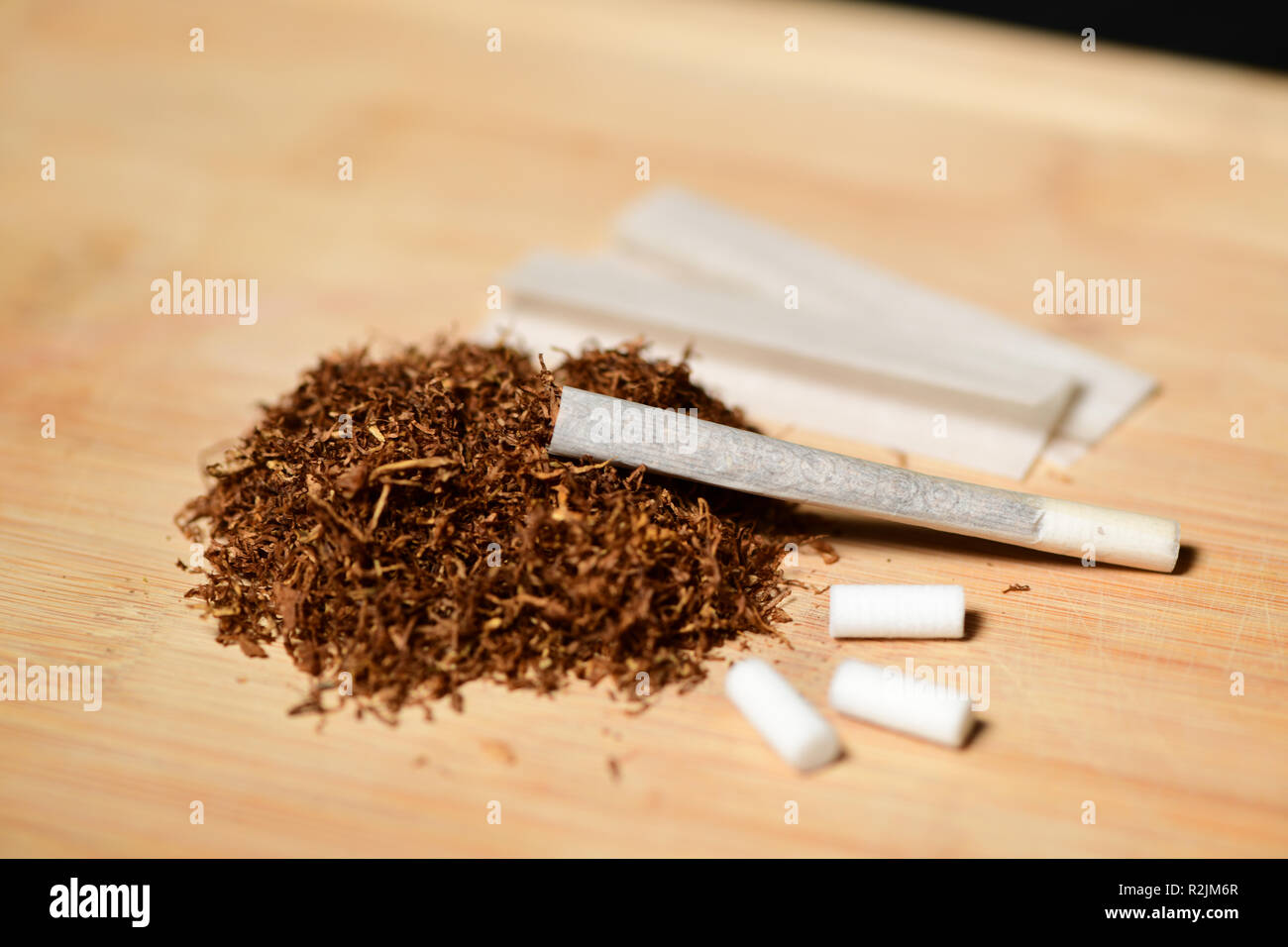 tabaco de liar, cenicero, boquillas y un cigarro encendido foto de Stock