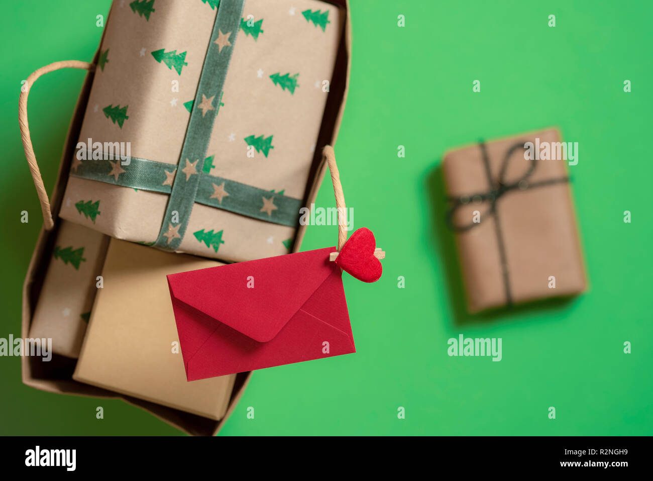 Bolsa de regalo lleno de cajas de regalos y sobres rojos encajada en la  empuñadura, y un regalo por separado sobre el fondo verde. Regalos de  Navidad y letras Fotografía de stock -