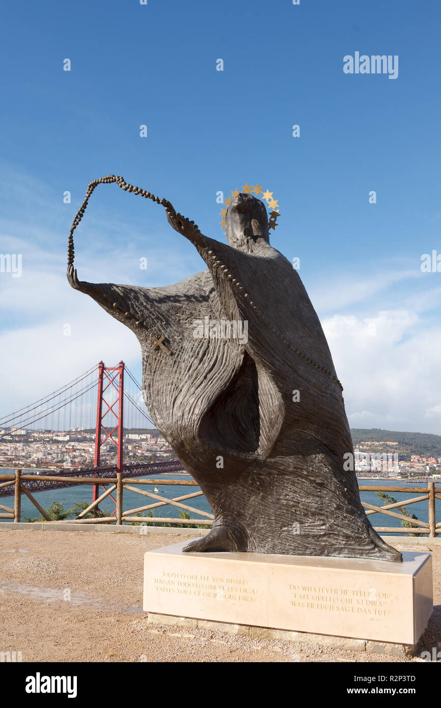 La estatua de la Virgen María y a la vista del puente 25 de abril delante del Santuario Nacional de Cristo Rei. Lisboa, Portugal Foto de stock