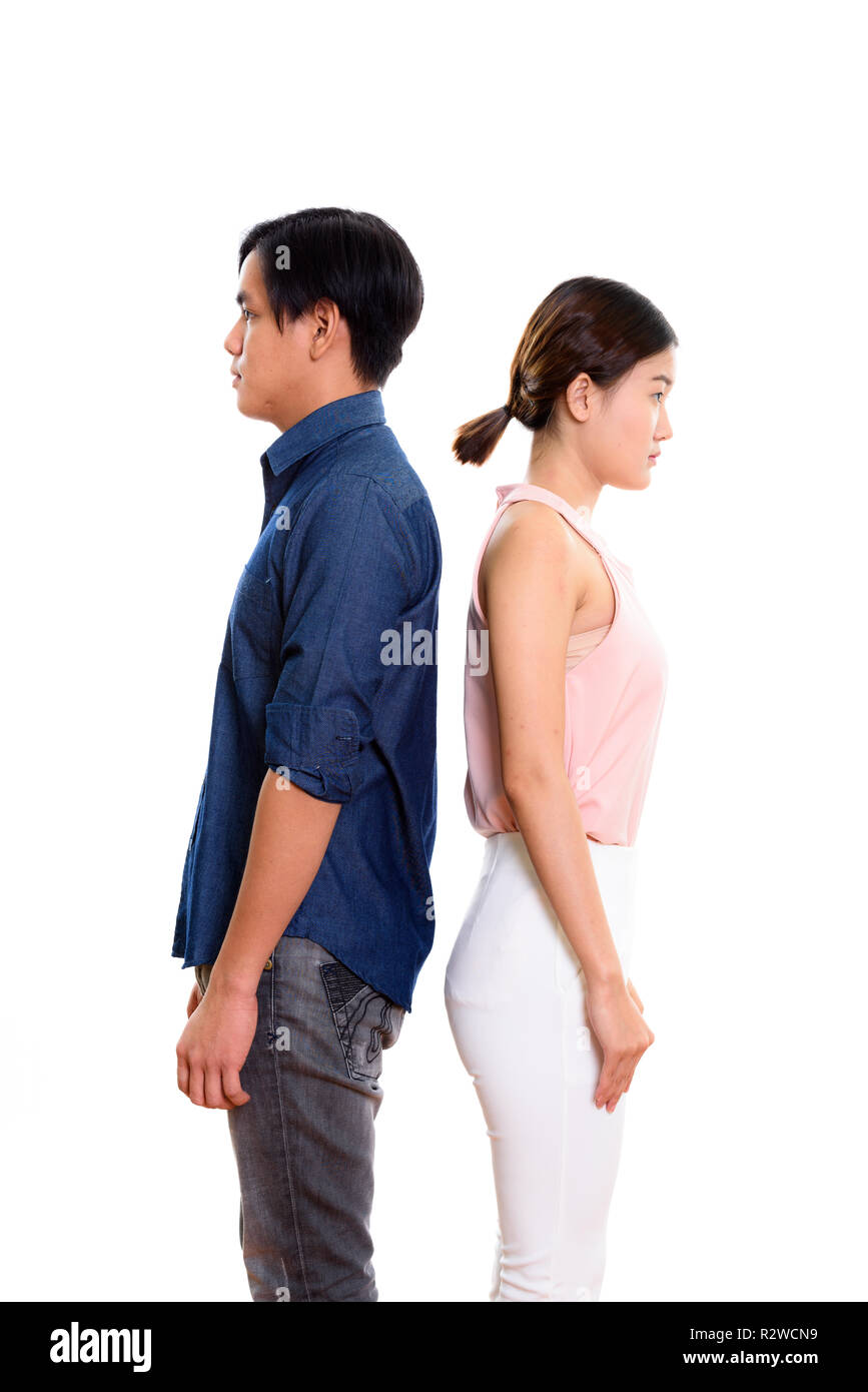 Vista del perfil de la joven pareja asiática con la espalda contra cada uno de ellos Foto de stock