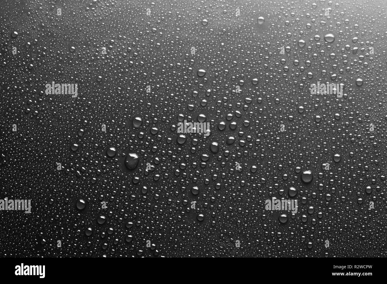 Gotas de agua sobre un fondo de textura de cristal oscuro Foto de stock