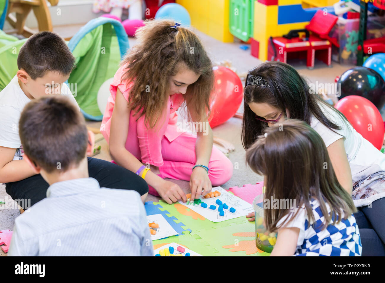 Grupo de niños aplicando coloridos plastilina durante la actividad educativa Foto de stock