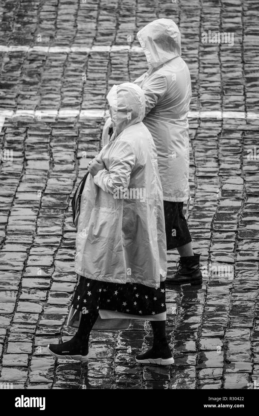 Los turistas en la lluvia en la Plaza Roja, Moscú, Rusia. Dos mujeres vistiendo ponchos con capuchas. Foto de stock