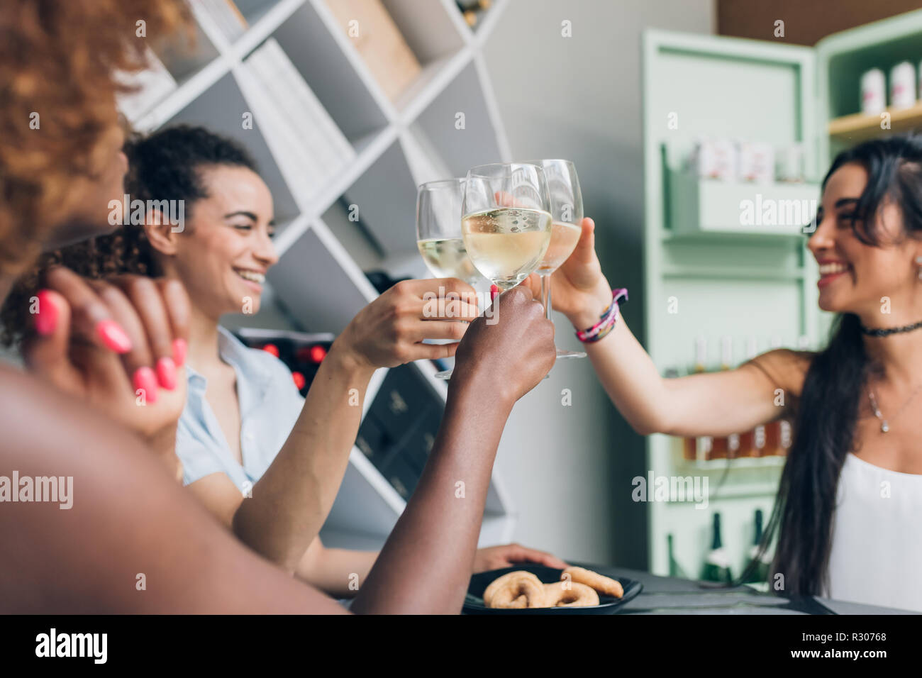Tres jóvenes mujeres indoor beber después de trabajar haciendo un brindis - celebrando el éxito de la relajación, después del trabajo, concepto Foto de stock