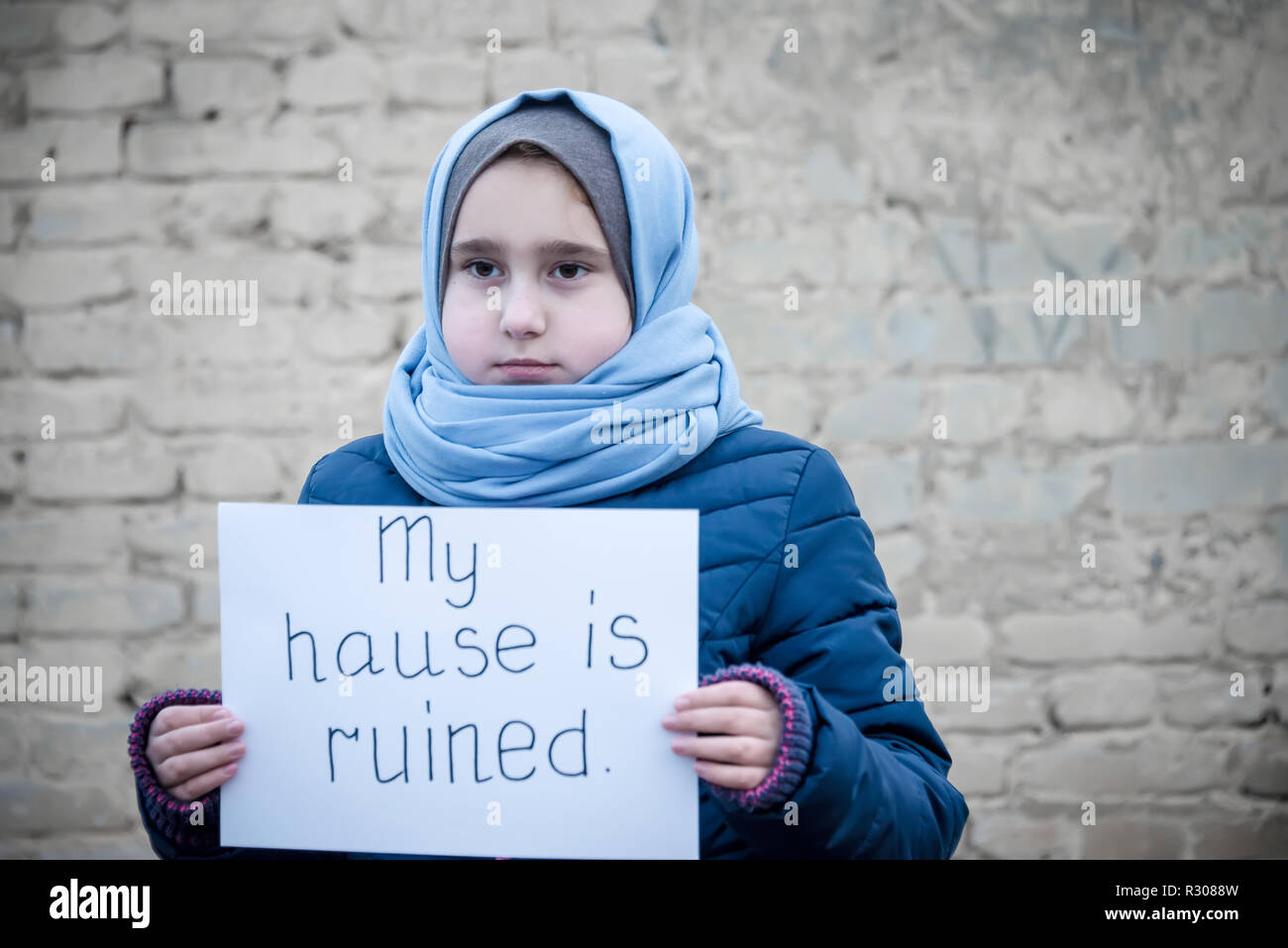 Niña refugiada con una inscripción en una hoja blanca de 'Mi casa está