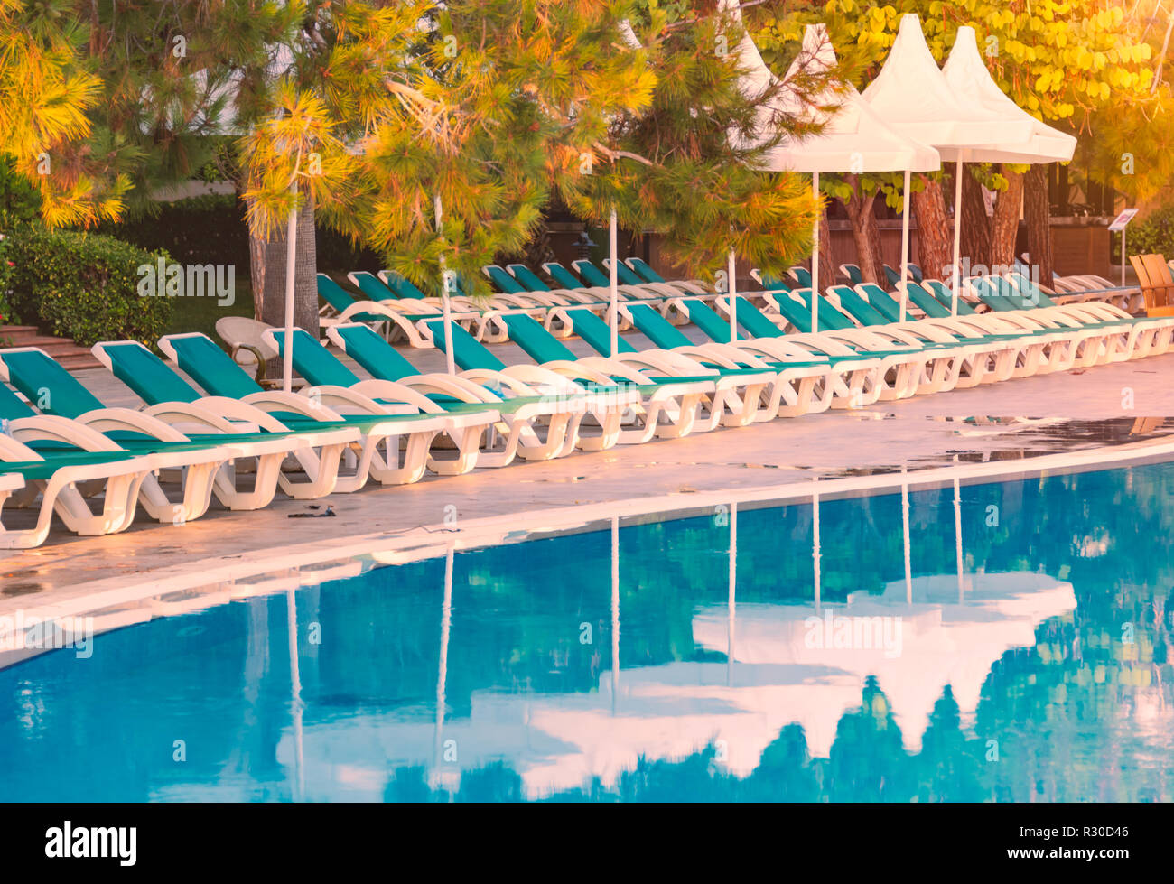 Hotel en Turquía con piscina en primer plano, blanco parasol sombrillas y sillas en segundo plano. Foto de stock