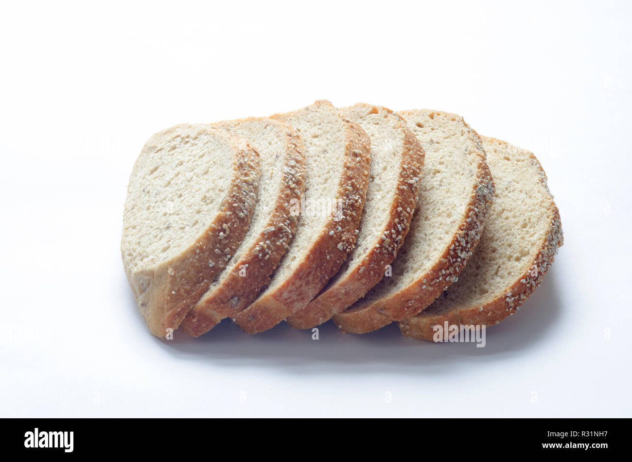 Rebanadas de granos antiguo panel toscano pan de grano entero con todo el trigo y la escanda harinas, granos enteros y semillas de lino en blanco Foto de stock