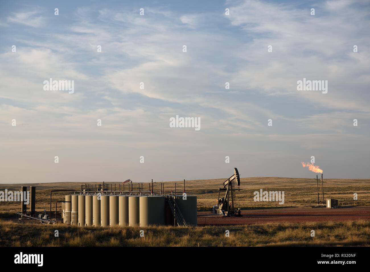 Pozo de petróleo crudo, la producción tanques, bomba jack, y la quema de gas natural en el esquisto Niobrara en Wyoming, Estados Unidos. Foto de stock