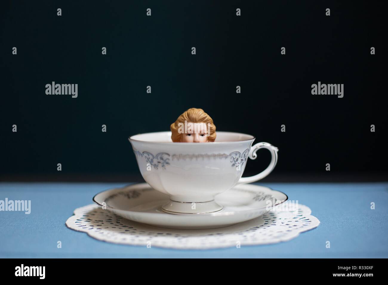Imagen surrealista de mujer (muñeca) en la taza de té. Foto de stock