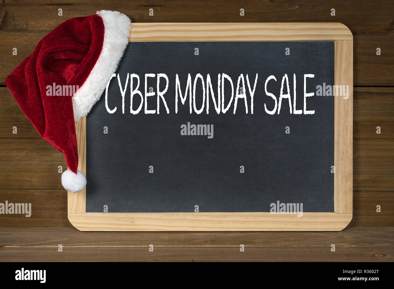 Rojo y blanco peludo gorro de Papá Noel sobre negro pizarra con copia espacio y madera rústica para Cyber Monday venta Foto de stock
