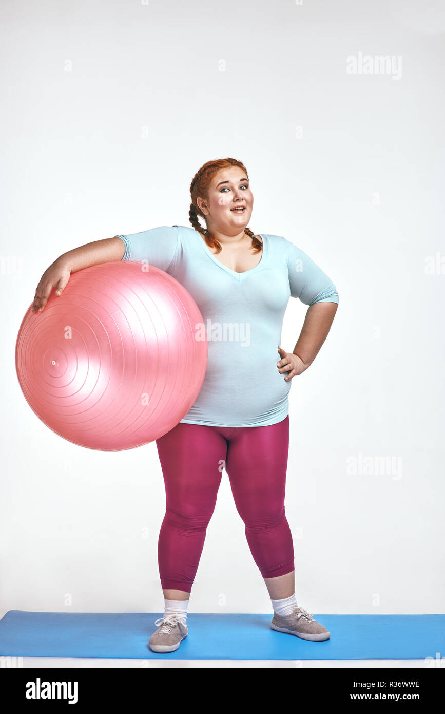 Foto divertida de divertidos, pelo rojo, chubby mujer sosteniendo un balón Foto de stock