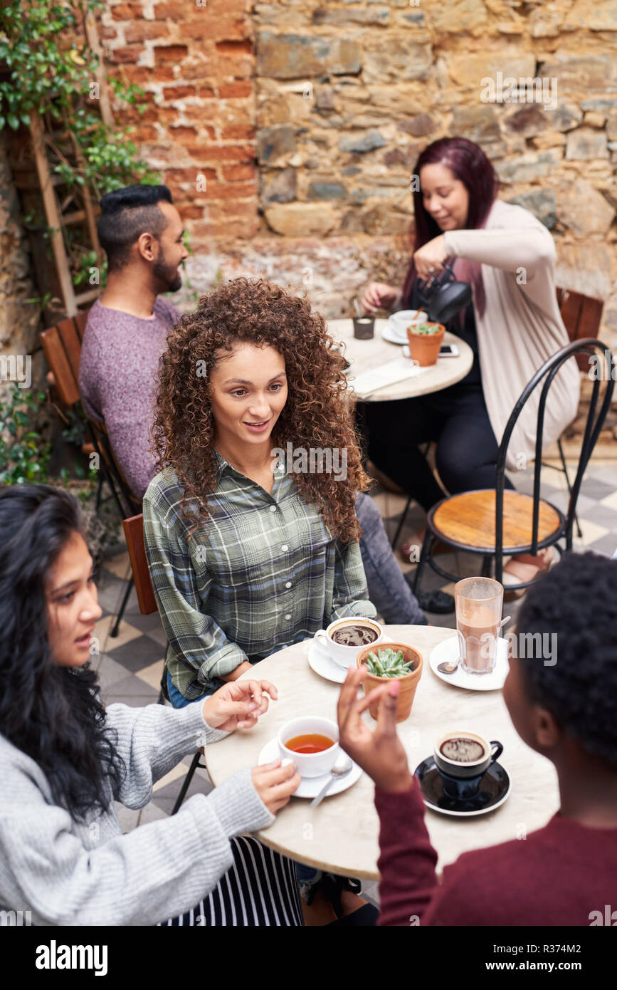 Mujer sonriente, conversando con amigos en un café patio Foto de stock