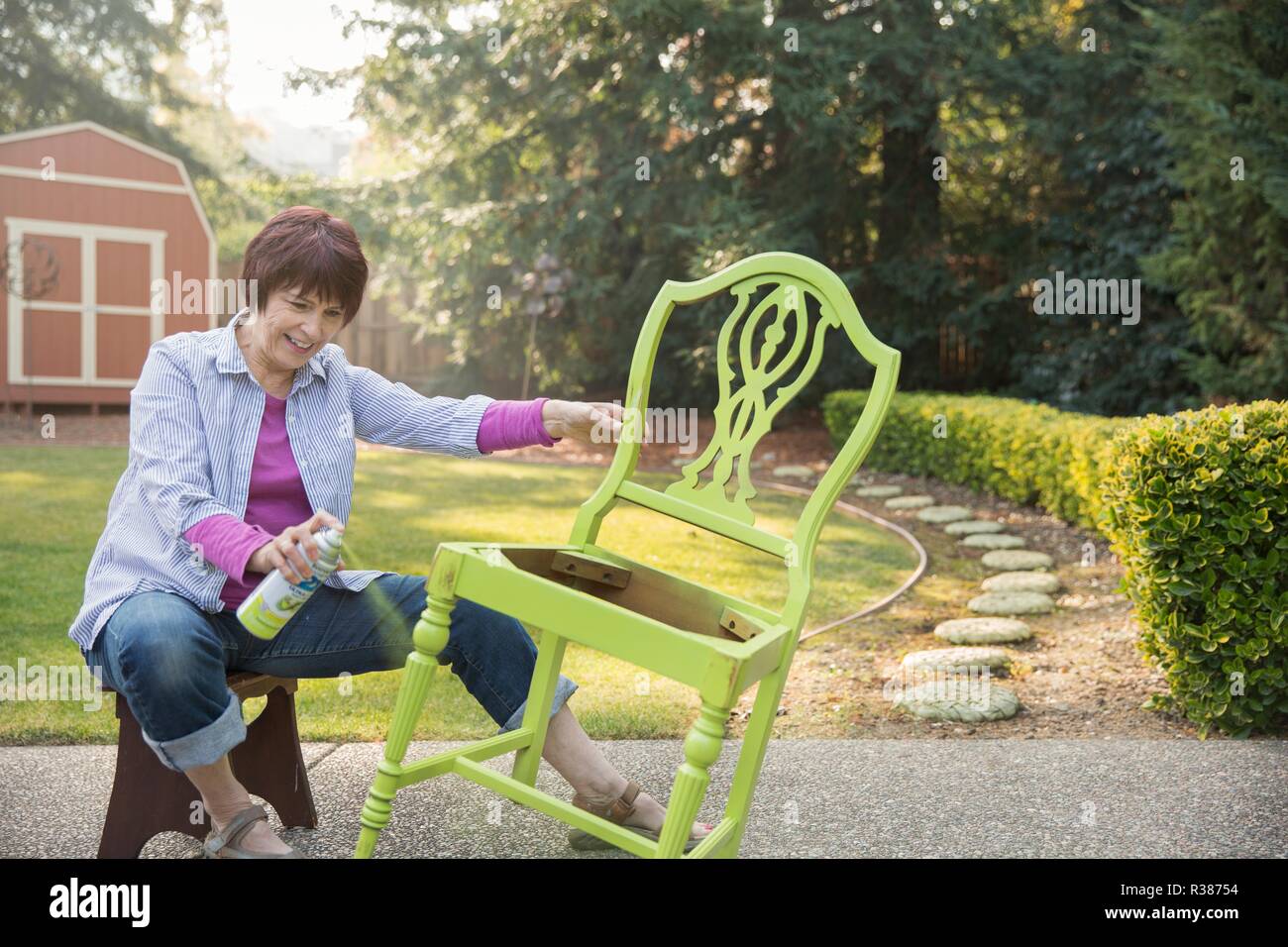 Una mujer madura artista restaurando una silla. Foto de stock