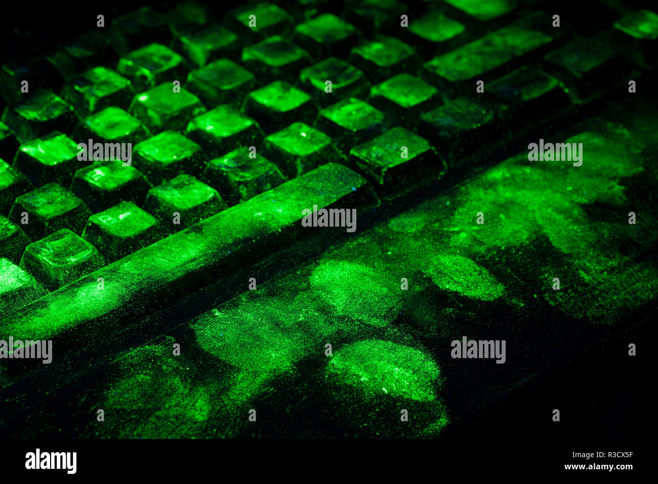 La ciencia forense, salpicaduras de huellas dactilares en el teclado del ordenador se muestran tras ser espolvoreado con pigmentos ultravioleta listo para resolver un crimen Foto de stock
