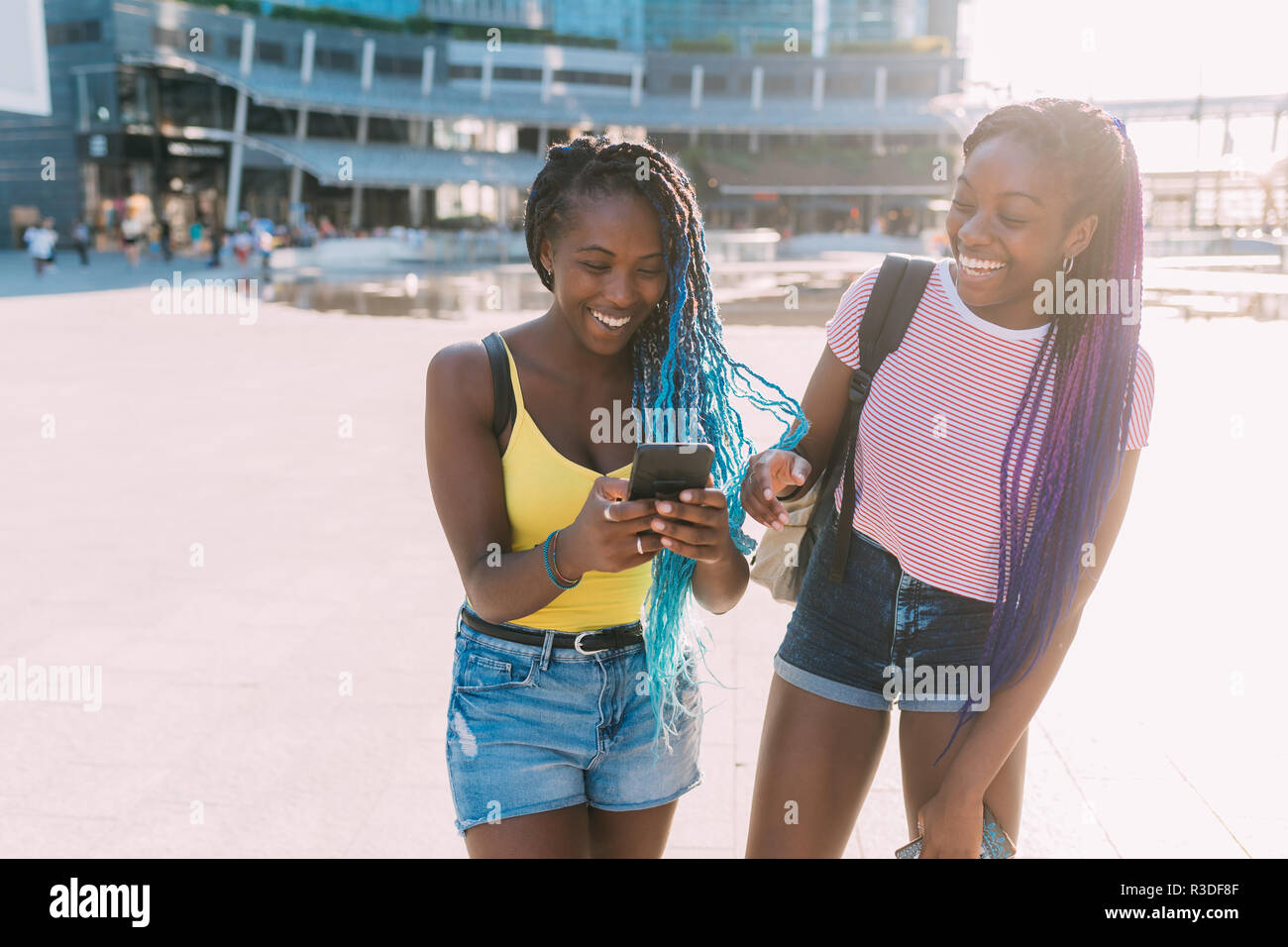 Dos mujeres hermanas outdoor utilizando smart phone divertirse - la felicidad, la tecnología, el concepto de red social Foto de stock