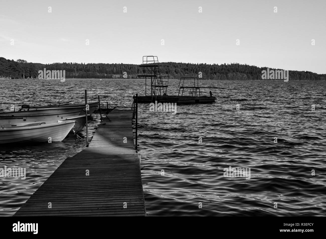 Un embarcadero de madera con un par de barcos que conducen a un pontón con plataformas de salto en Teåkersjön, Dalsland, Suecia Foto de stock