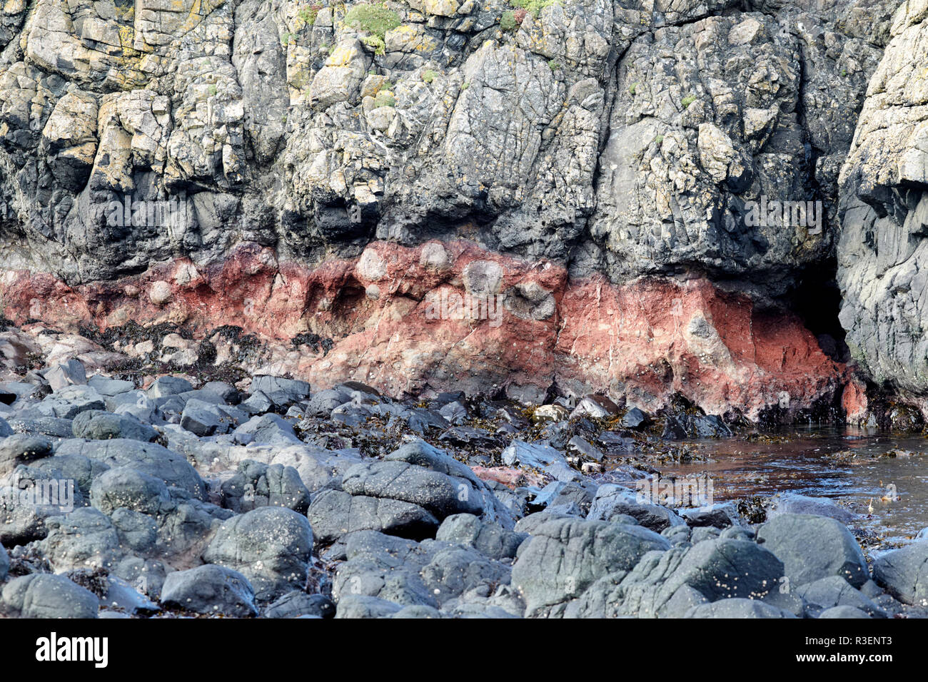 Estratos de roca basáltica downfaulted capas incluyendo rojo banda formada de las cenizas enterradas Ballintoy condado de Antrim de Irlanda del Norte Foto de stock
