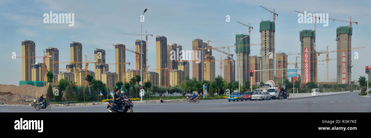 China, Ningxia, Yinchuan. Vista panorámica de un grupo de edificios altos de apartamentos en las diversas etapas de la construcción de grúas. Foto de stock