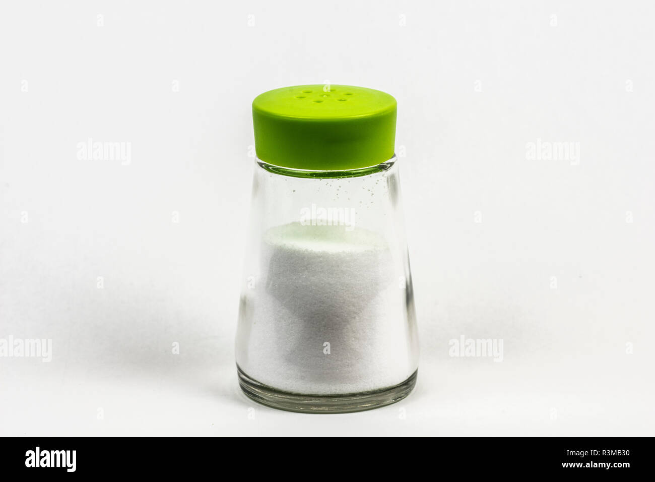 Una mini botella de sal con tapa verde de plástico. Aislados en blanco. Foto de stock