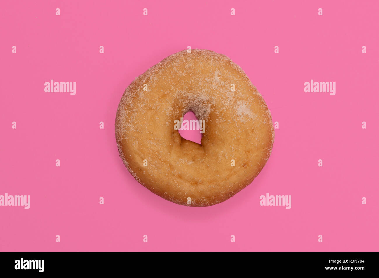 Donut recubierto de azúcar con fondo rosa Foto de stock