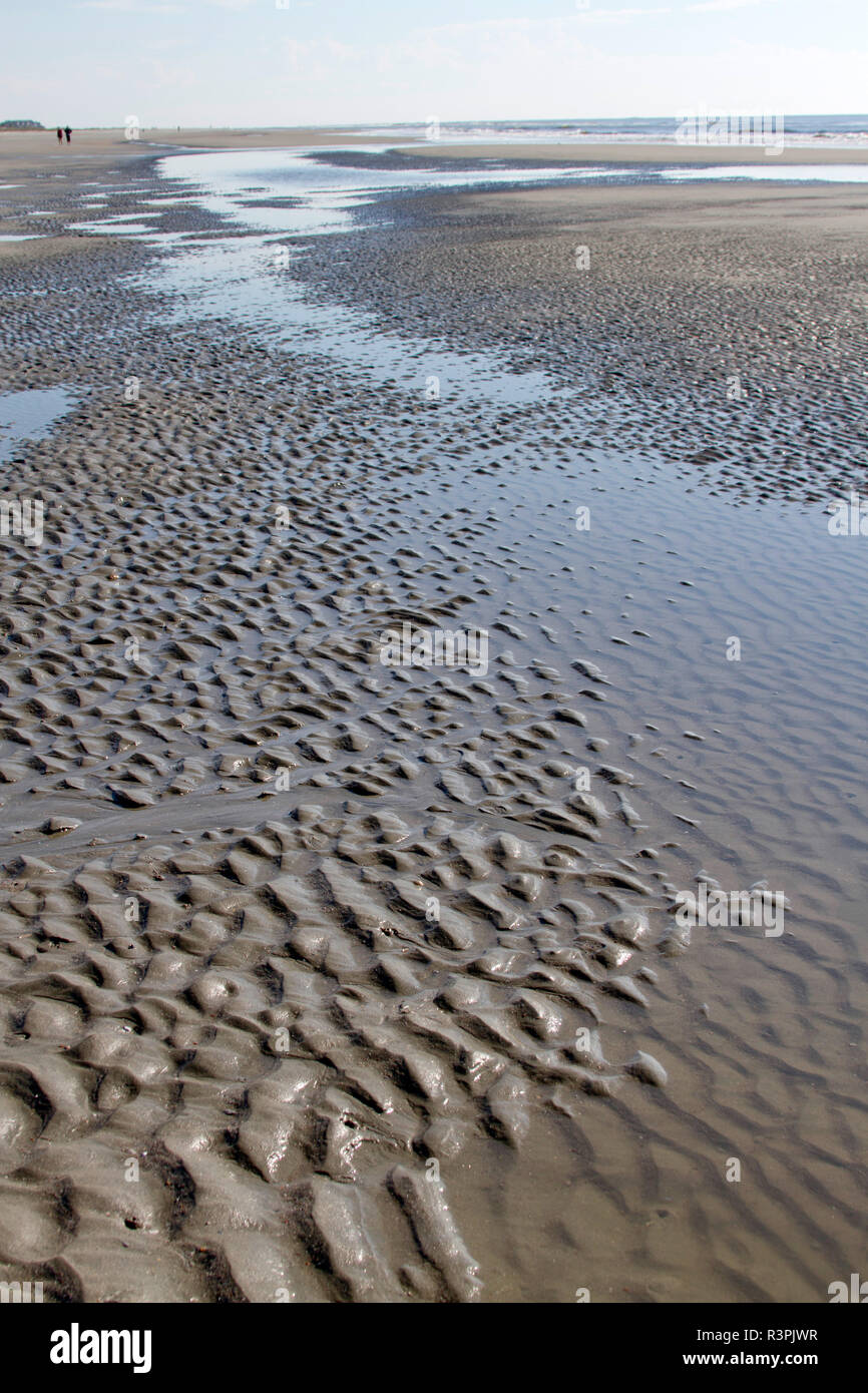 Textura artística Piscina de marea en la playa por el mar con olas altas caminando en la distancia Foto de stock