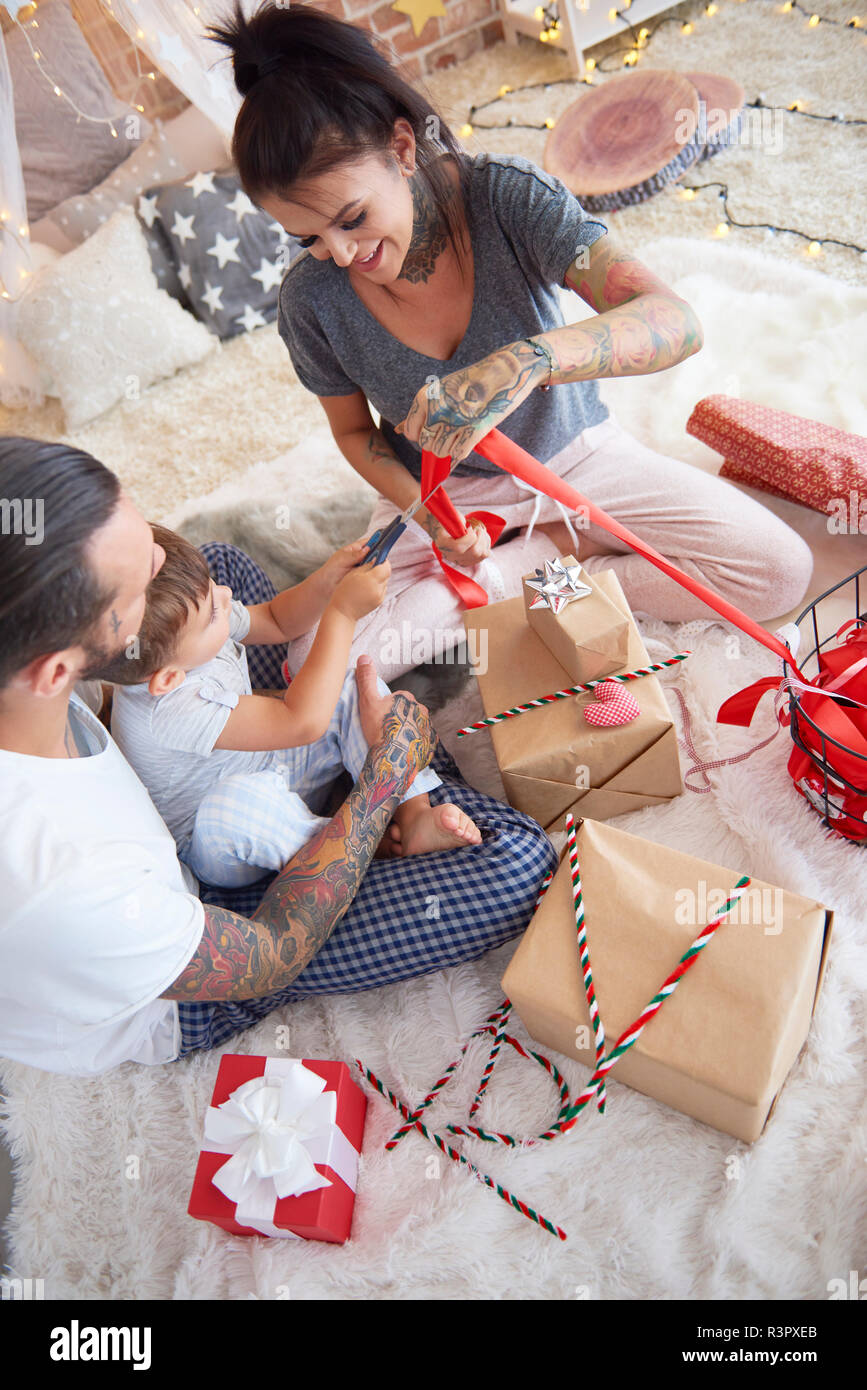 Niño abriendo regalo de Navidad con sus padres en la cama Foto de stock