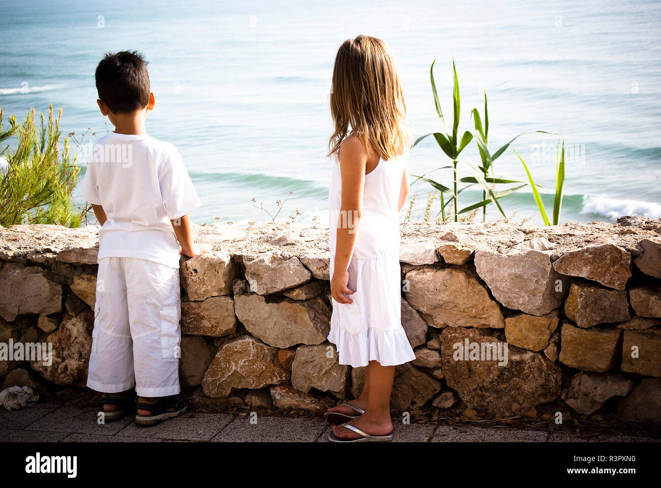 Dos niños vestidos de blanco mirando el mar Fotografía de stock - Alamy