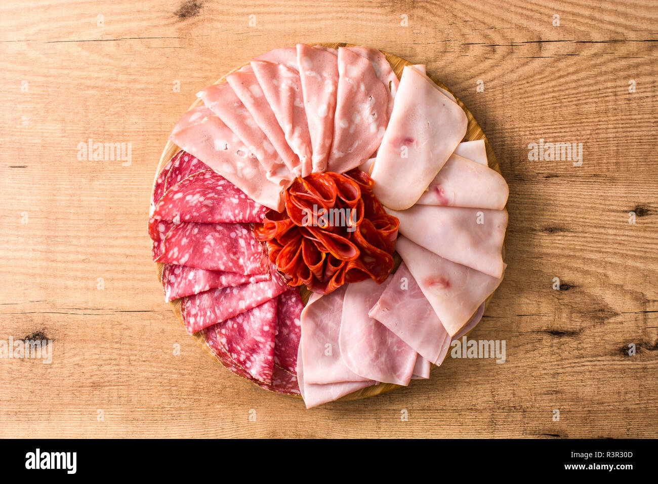 Tabla de cortar la carne en frío sobre la mesa de madera. Jamón, salami, salchichas, mortadela y Turquía. Vista desde arriba. Foto de stock