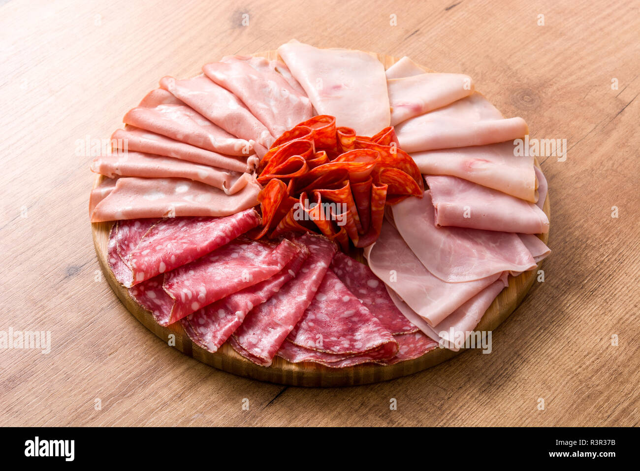 Tabla de cortar la carne en frío sobre la mesa de madera. Jamón, salami, salchichas, mortadela y Turquía Foto de stock