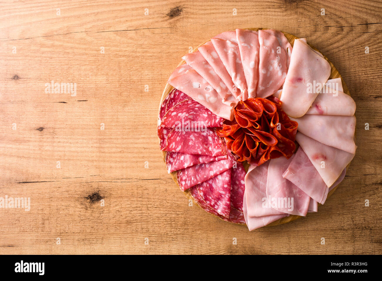 Tabla de cortar la carne en frío sobre la mesa de madera. Jamón, salami, salchichas, mortadela y Turquía. Vista desde arriba. Copyspace Foto de stock