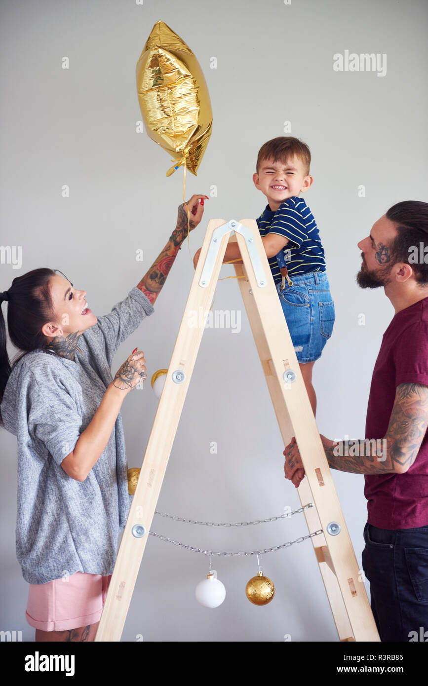 Familia moderna decorar la casa en época de Navidad usando la escalera como árbol de Navidad Foto de stock